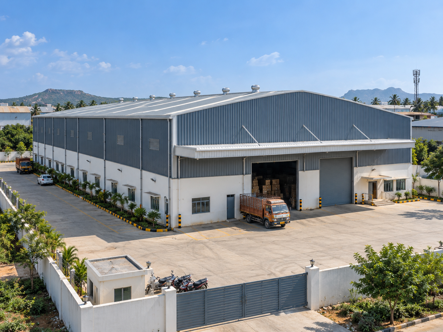 Completed industrial steel building with large roof span, wall cladding, loading openings and paved project surroundings.